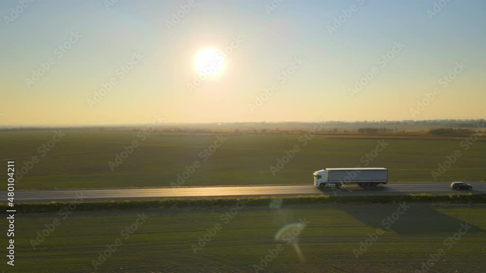 Aerial view of semi-truck with cargo trailer driving on highway hauling goods in evening. Delivery transportation and logistics concept Aerial view of semi-truck with cargo trailer driving on highway hauling goods in evening. Delivery transportation and logistics concept