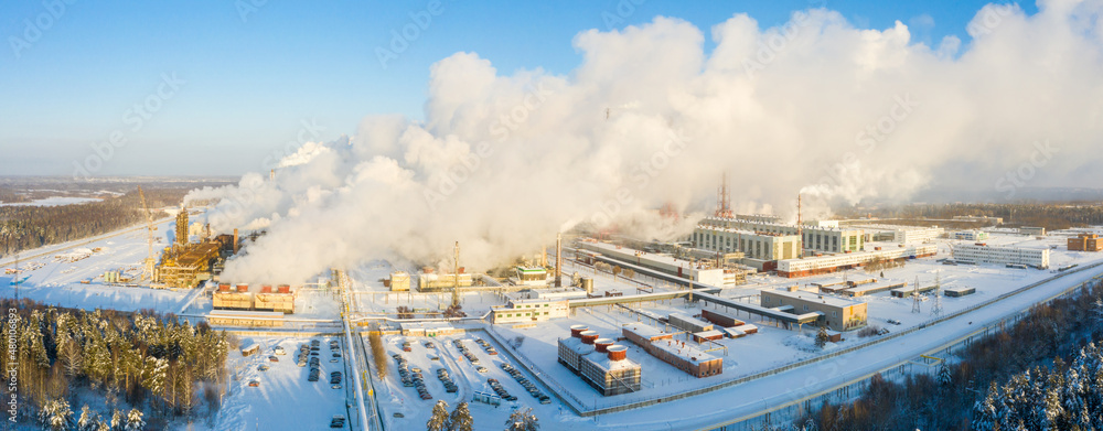 Fototapeta premium Industrial landscape. Panoramic view of the technological pipe and industrial infrastructure. Chemical production with red-white pipes and smoke is coming. Production buildings.