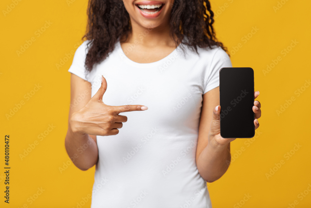 Φωτογραφία Black woman pointing at smartphone with black screen, cropped, mockup for your w