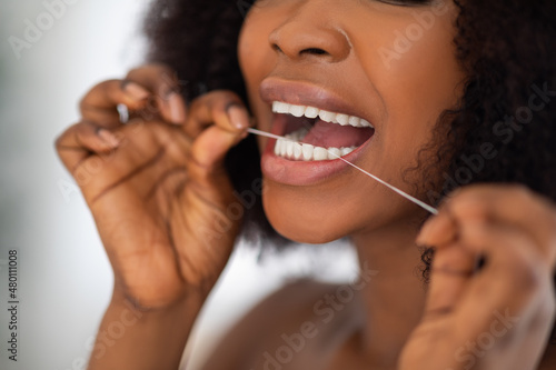 Unrecognizable Afro woman cleaning teeth with dental floss at home  closeup. Oral hygiene  wellness  healthy lifestyle