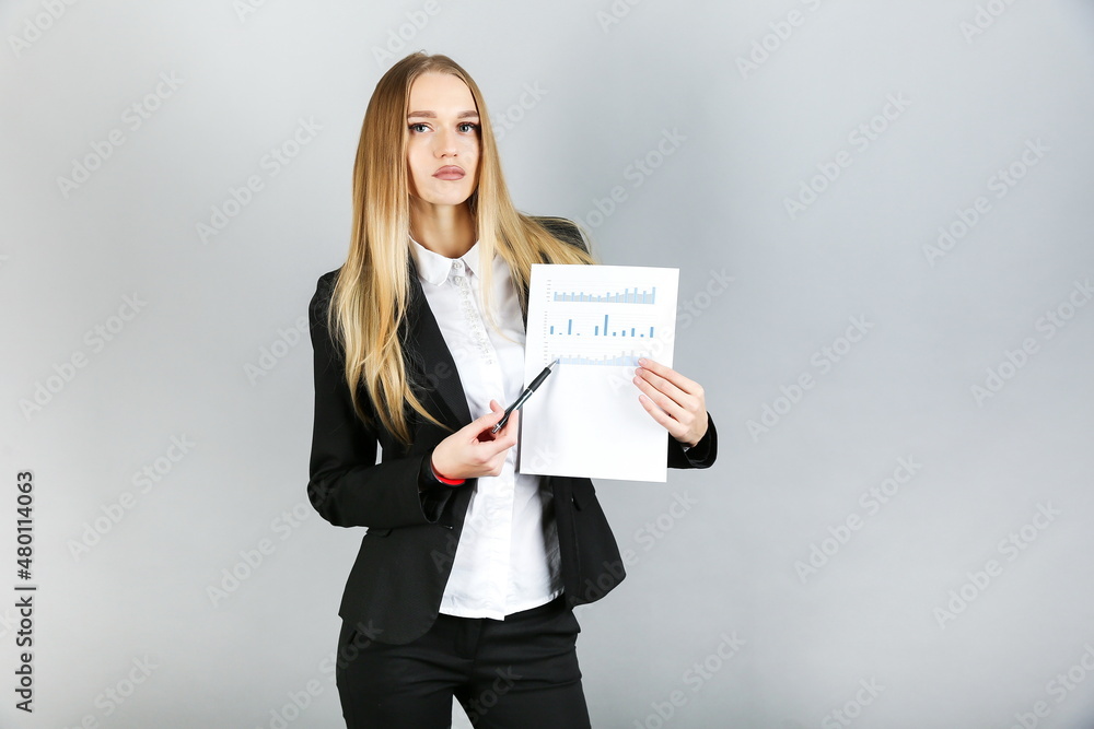 beautiful business woman holds paper chart and pen on gray background. female shows sales growth. financial analyst makes a presentation. beautiful business woman holds paper chart and pen on gray background. female shows sales growth. financial analyst makes a presentation.