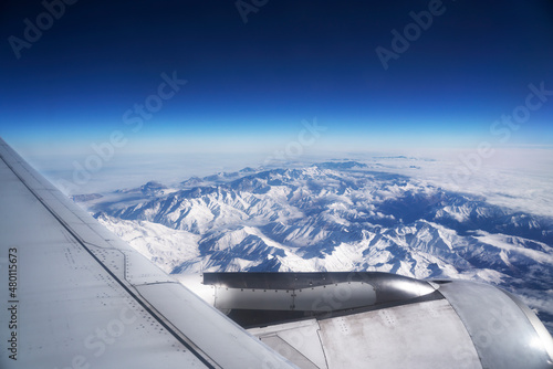 Airplane view of mountains with snow and wing
