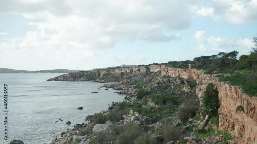 AERIAL: Steep Coastline in Mellieha Bay with Sharp Limestone Rocks at the Bottom of Shore AERIAL: Steep Coastline in Mellieha Bay with Sharp Limestone Rocks at the Bottom of Shore