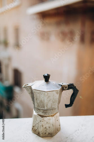 old steel Italian geyser coffee maker on a marble windowsill. moka pot closeup. coffee prepared in a geyser coffee maker is cooled in the window
