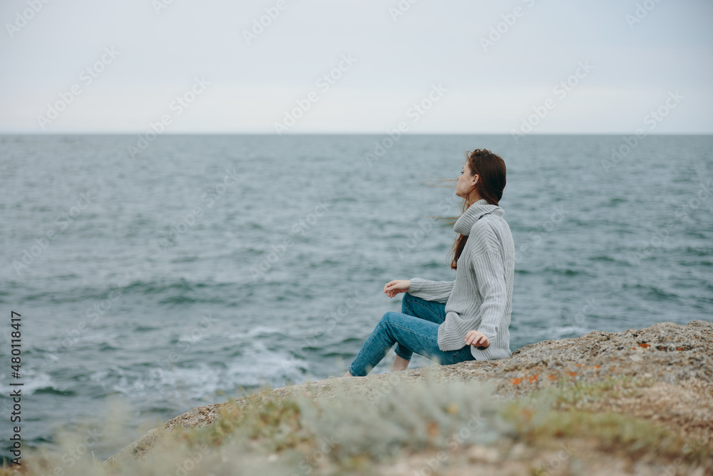 pretty woman seated on the coast sweater landscape Relaxation concept