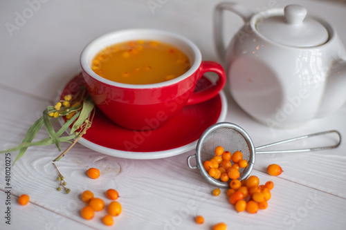 Herbal hot tea with buckthorn and honey on white wooden background. Hot drinks with vitamins