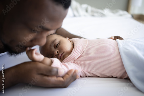 Black father kissing forehead of newborn daughter
