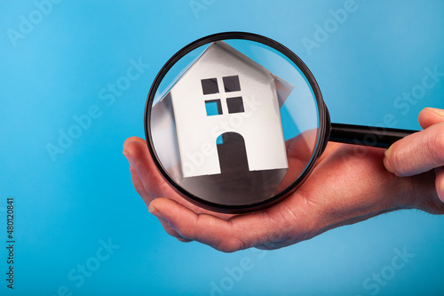 Man's hand with a magnifying glass near the house.
