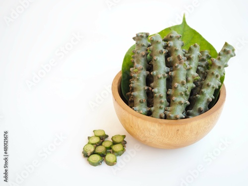 Tinospora cordifolia (Thai herb) and green leaves in wood bowl on white background. closeup photo, blurred. photo