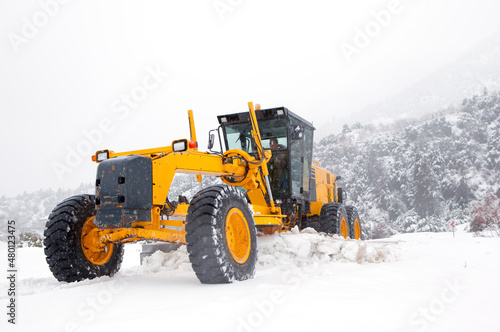 The bulldozer or grader cleans snow on the road © muratart