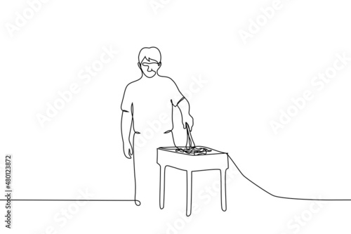 man frying meat on the grill turning the pieces with kitchen tongs - one line drawing vector. barbecue concept, summer outdoor recreation, street food