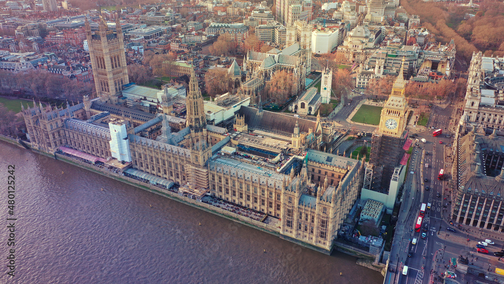 Fototapeta premium Aerial drone photo of iconic City of Westminster with houses of Parliament, Big Ben and Westminster Abbey in front of river Thames at sunset, London, United Kingdom