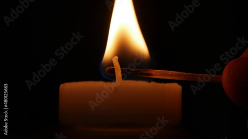 Lighting a Candle with a Fired Match. Man Illuminating with a Candle a Dark Room in Time of an Accidental Power Failure. photo