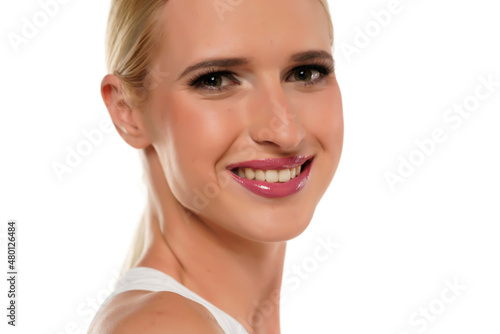 Young smiling blond woman with tied hair and makeup on a white