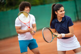 Beautiful young people are playing tennis as a team on tennis court outdoors. People sport concept