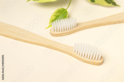 Two wooden bamboo eco friendly toothbrushes and green leaf on purple background. Dental care and zero waste concept. Flat lay  top view  copy space