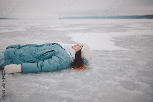 beautiful young girl lying on ice, frozen lake, girl lying in snow