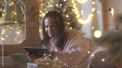 Young pretty woman happy smile on digital tablet at night cozy home enjoy festive winter season. 3840x2160