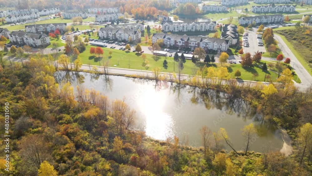 Aerial view of an apartment housing community with woods and ponds and lakes during the fall and autumn time and a highway nearby Aerial view of an apartment housing community with woods and ponds and lakes during the fall and autumn time and a highway nearby