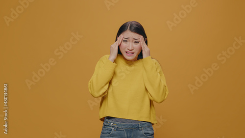Fotografia Unhappy adult rubbing temples to cure headache problem, suffering from tension and migaine in studio