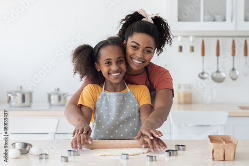 Adorable black mom and child making pastry together at home