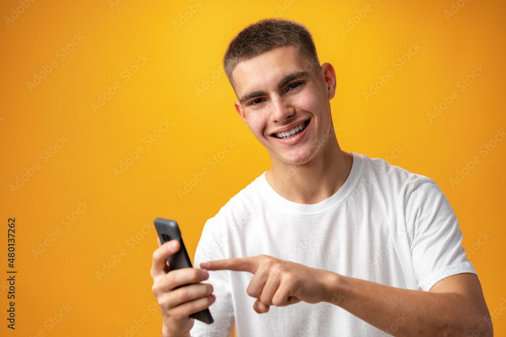 Young casual man teenager using a smartphone against yellow background Young casual man teenager using a smartphone against yellow background