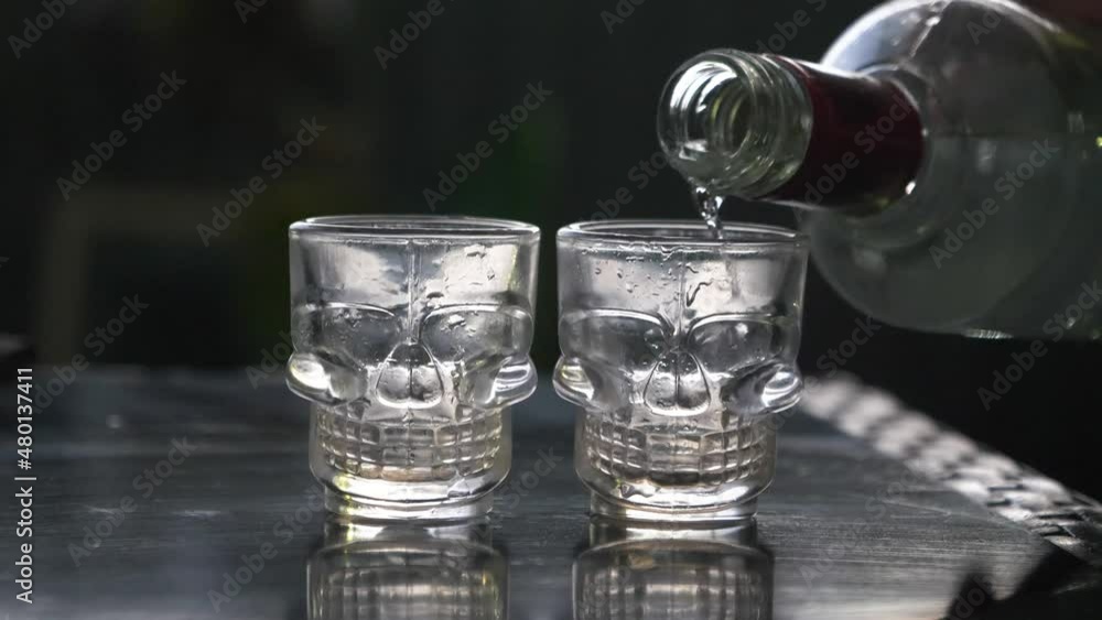 Pouring a Shot of Liquor from Vodka Bottle Alcohol into a Shot Glass at a Beer Pub Bar During Night Pouring a Shot of Liquor from Vodka Bottle Alcohol into a Shot Glass at a Beer Pub Bar During Night