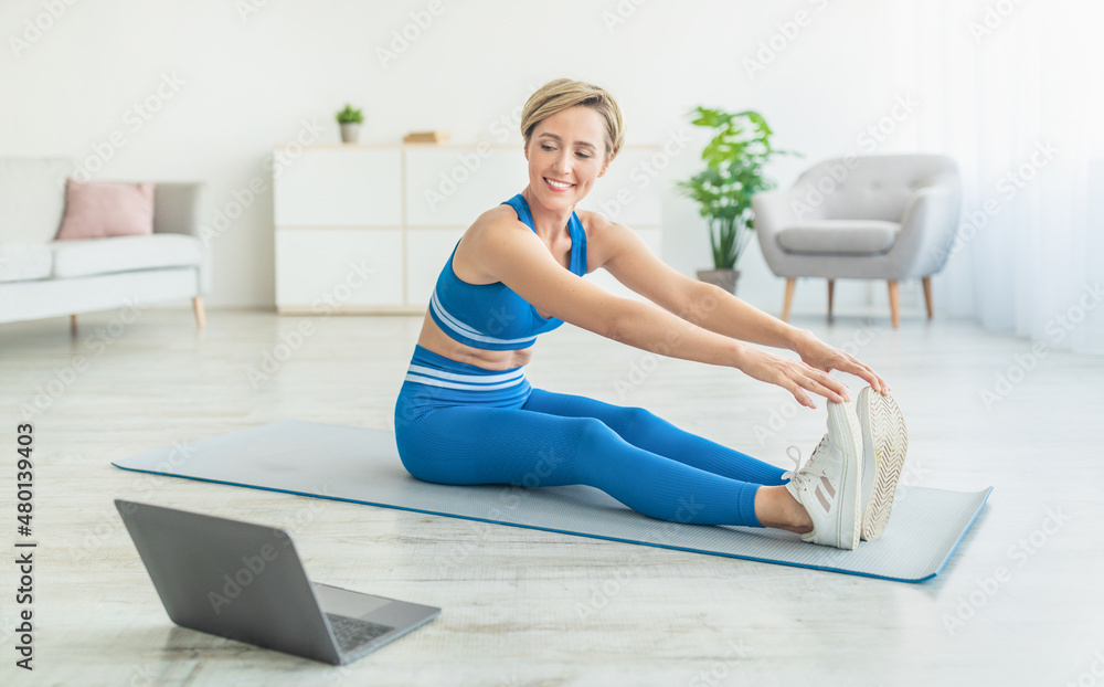 Happy Woman In Sportswear Stretching Legs On Mat Using Pc Happy Woman In Sportswear Stretching Legs On Mat Using Pc