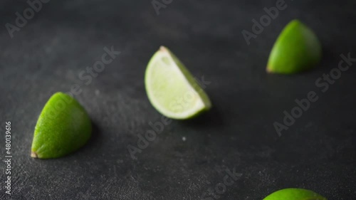 The lime falls on a black surface and shatters into pieces.