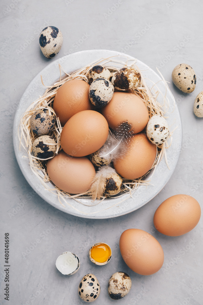 Eggs. Raw organic farm chicken and quail eggs in bowl on gray stone background Eggs. Raw organic farm chicken and quail eggs in bowl on gray stone background