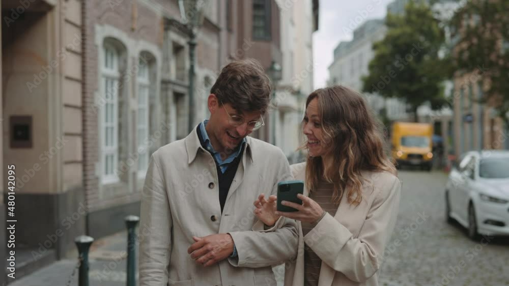 Mature couple walking on street and using smartphone Mature couple walking on street and using smartphone