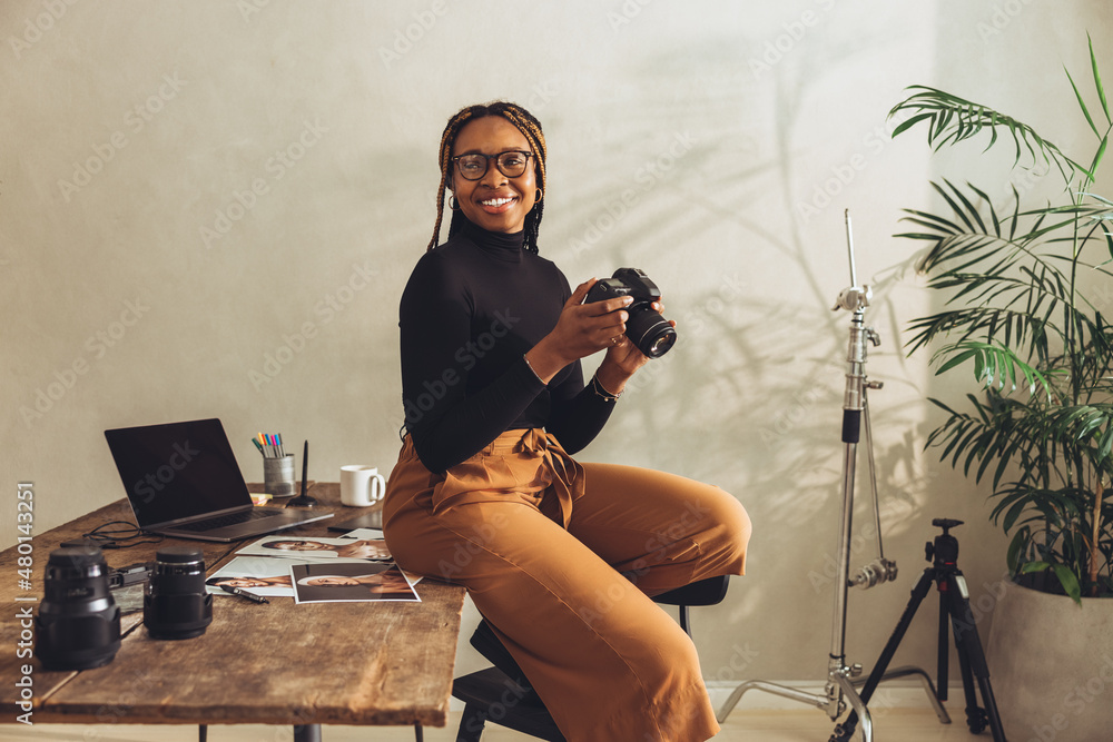 Happy female photographer smiling in her office - obrazy, fototapety, plakaty 