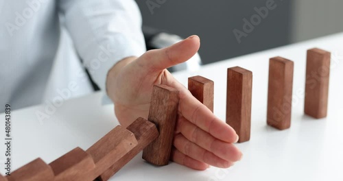 Risk and strategy in business is hand stopping the fall of wooden block