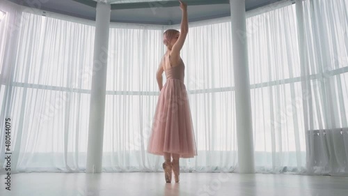 The ballerina dances against the background of large panoramic windows.
