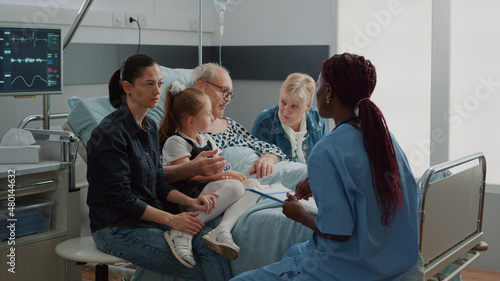 Fotografía Medical assistant talking about diagnosis with woman in visit, explaining healthcare treatment in hospital ward