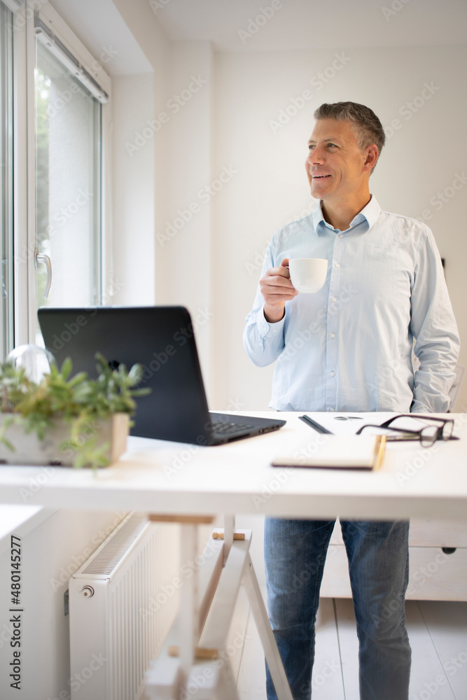 Businessman standing behind bar table with notebook and taking coffee break Businessman standing behind bar table with notebook and taking coffee break