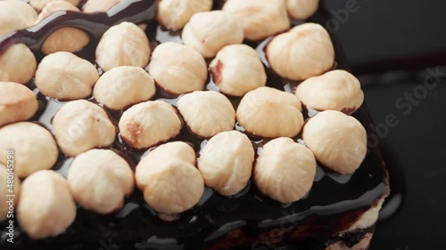 Cake with hazelnuts is poured with chocolate topping.