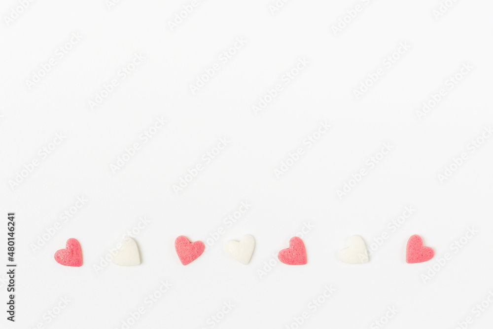 Pink and white heart-shaped sugar candies on white background minimalistic valentine`s day greeting card
