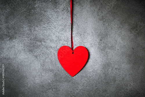 Minimalistic decoration, red heart over textured grey background