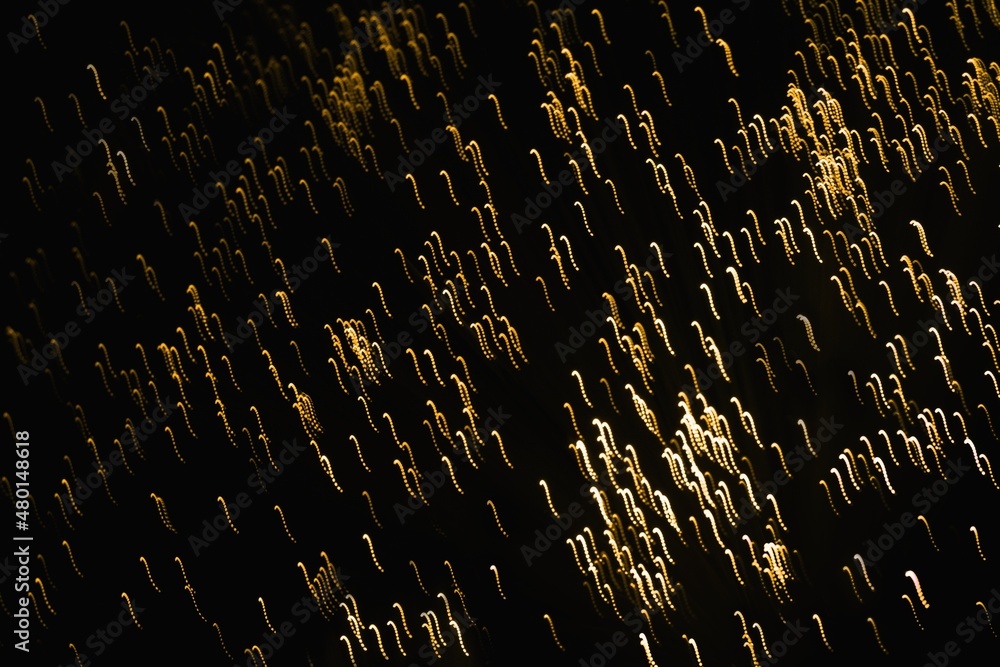 Fototapeta premium Abstract blurred golden glittering light on the black background