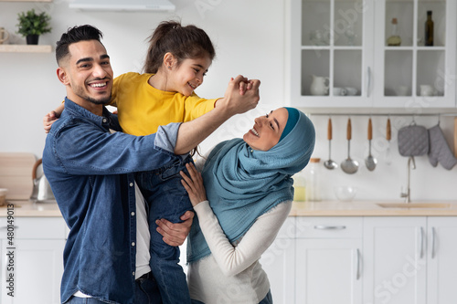 Portrait Of Cheerful Middle-Eastern Family Of Three Haaving Fun In Kitchen Together