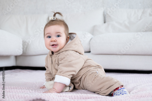 Adorable baby in warm overall sitting on the blanket