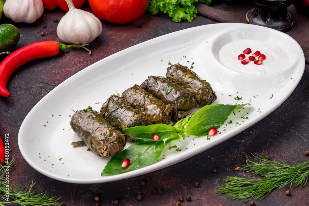 Dolma georgian kitchen with sour cream on white plate on dark table Dolma georgian kitchen with sour cream on white plate on dark table