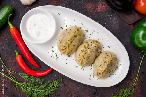 Manty with beef on white plate with sour cream, uzbek cuisine top view photo