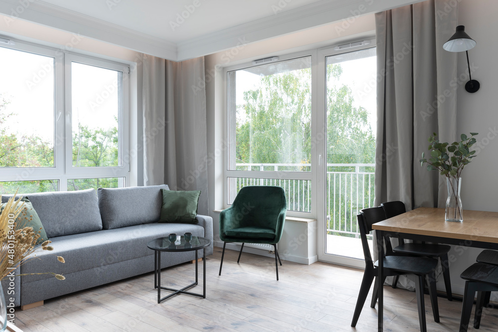 Interior of living room with big window, comfortable sofa, armchair and wooden floor. Scandinavian architecture in cozy room . Interior of living room with big window, comfortable sofa, armchair and wooden floor. Scandinavian architecture in cozy room .