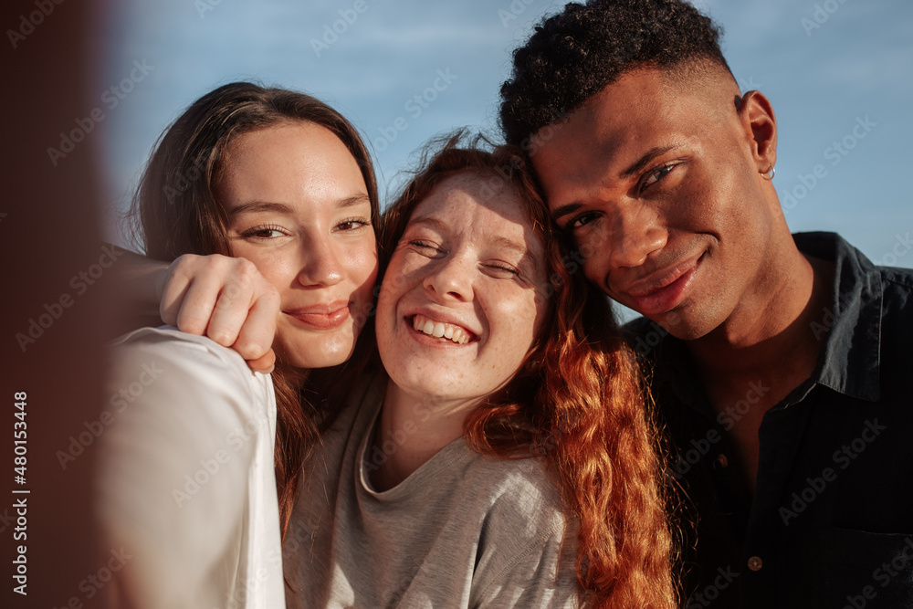 Multicultural friends taking a group selfie together Multicultural friends taking a group selfie together