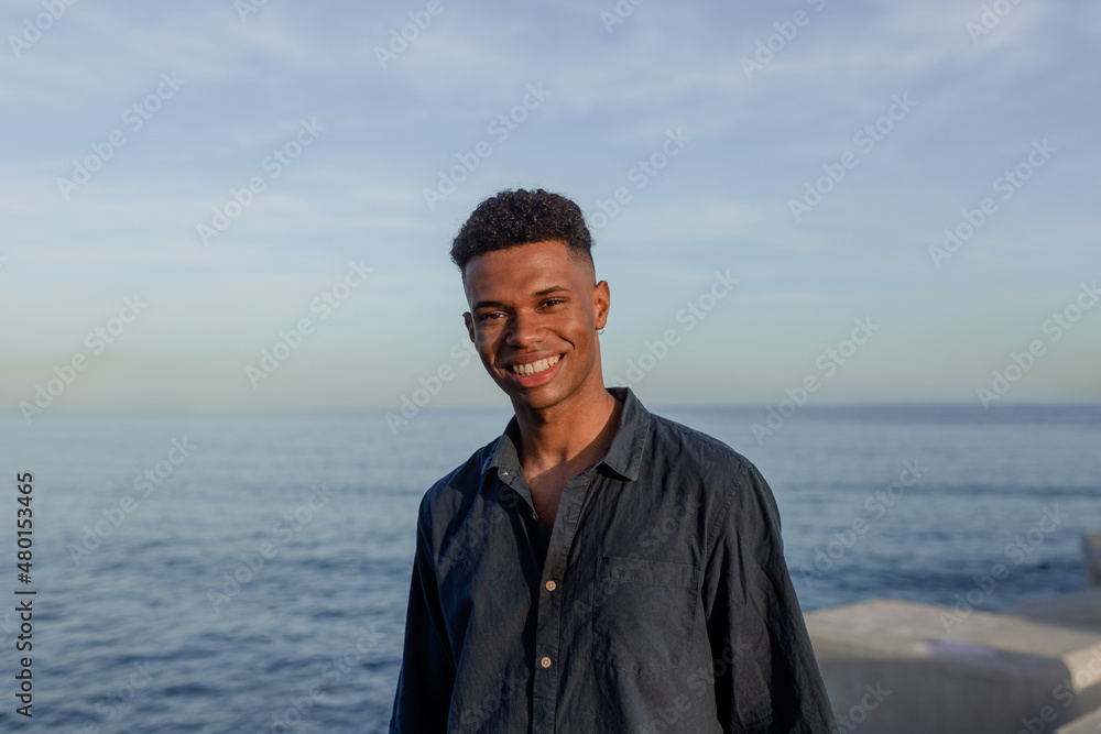 Happy young man smiling at the camera by the seaside