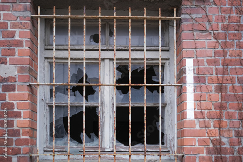 Vergittertes Fenster mit zerschlagenen Scheiben