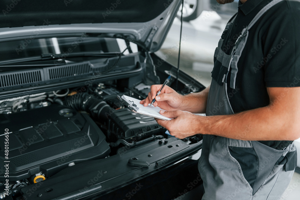 Modern vehicle. Man in uniform is working in the autosalon at daytime