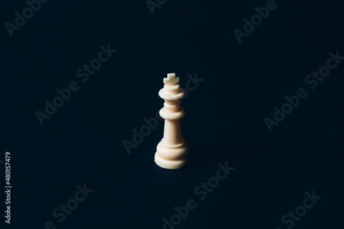White chess queen on a black background. Abstract background. Chess piece. Concept of leadership, loneliness